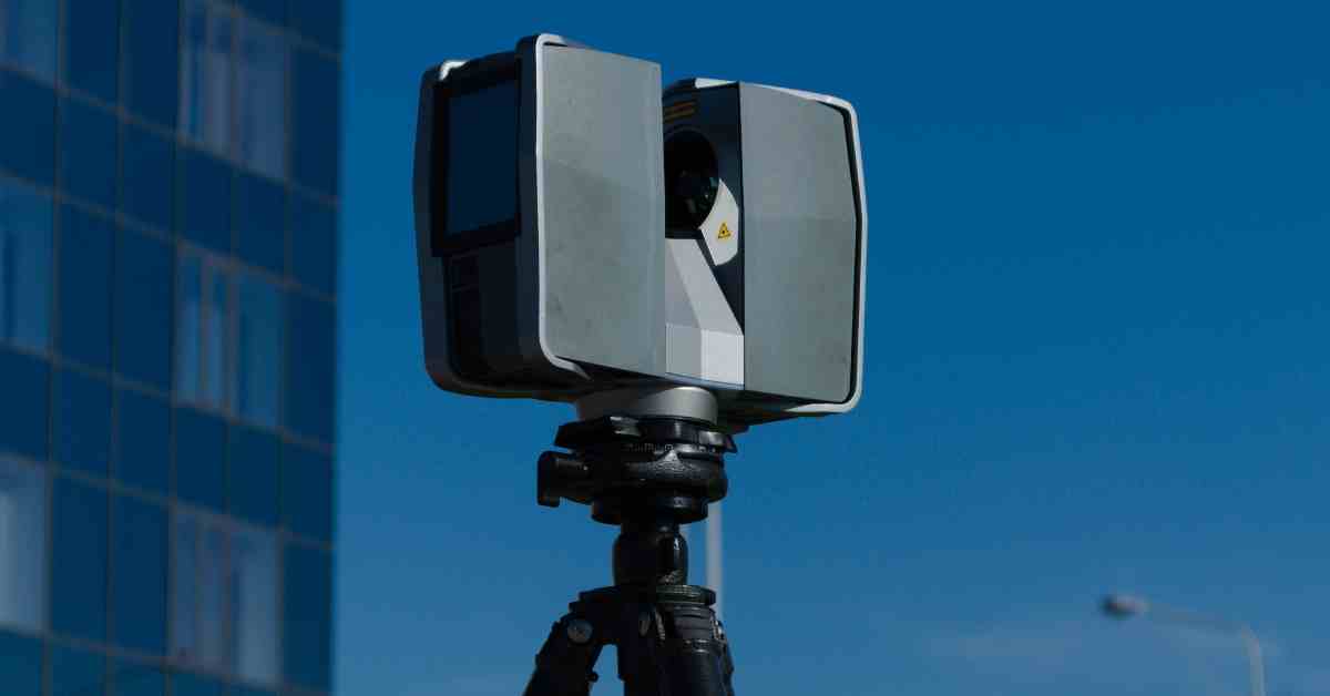 A laser scanner set up on a tripod. The tool is currently scanning outdoors near an office building